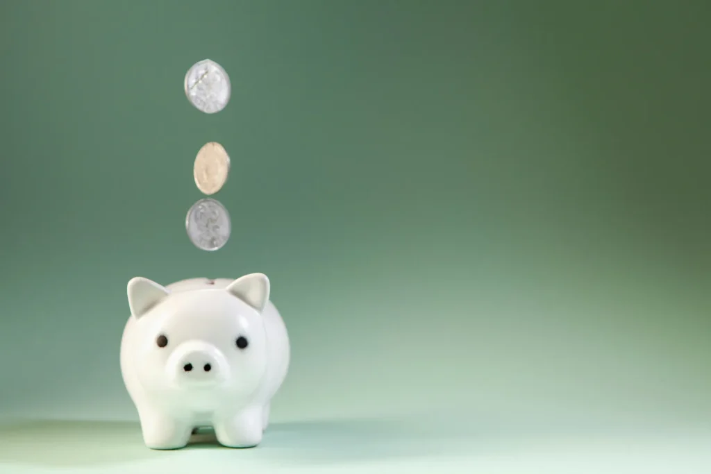 Coins falling into a white piggy bank